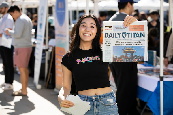 girl holding up the daily titan newspaper